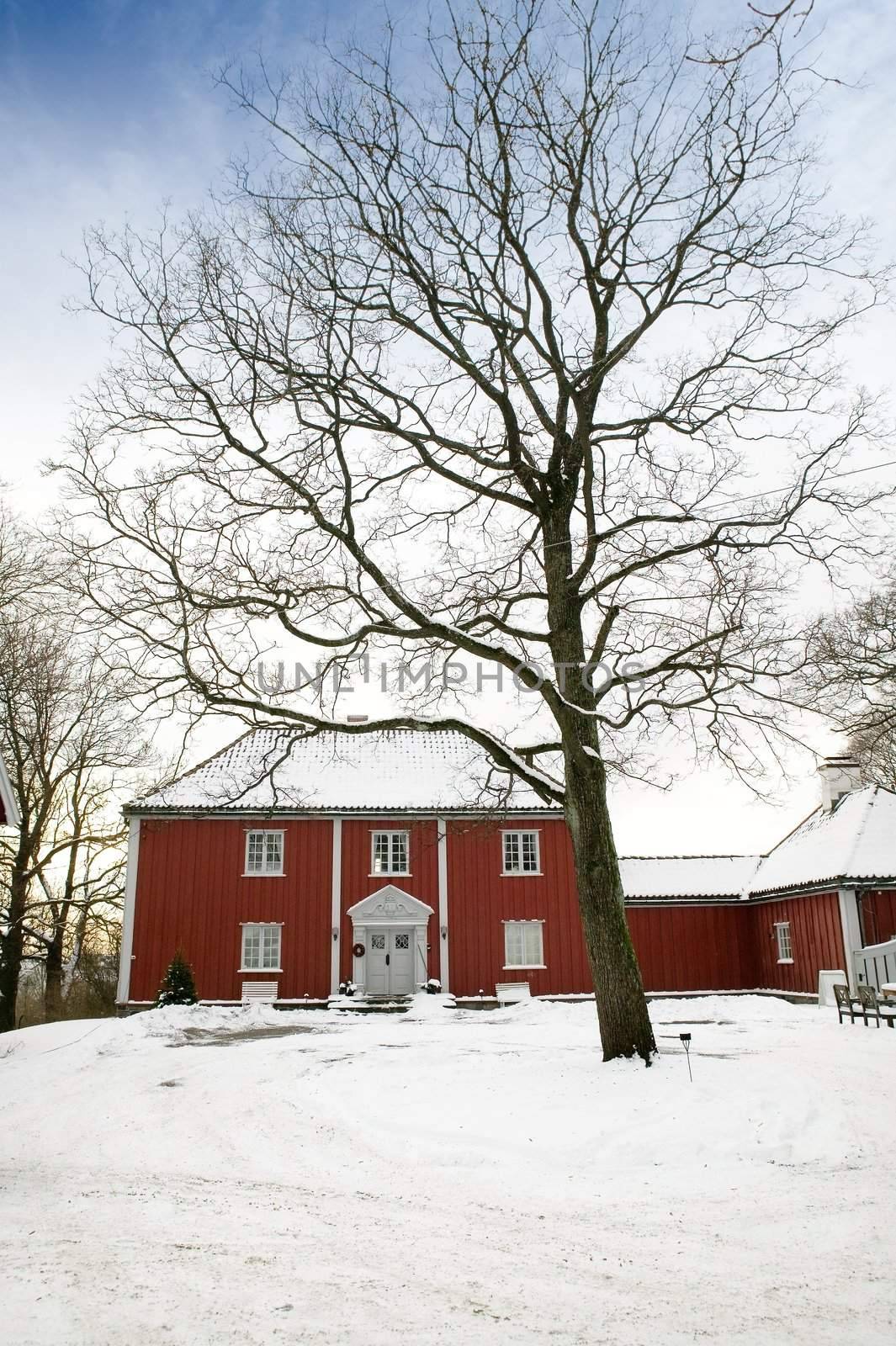 A large red wooden house in a nice neighborhood surrounded by bushes.