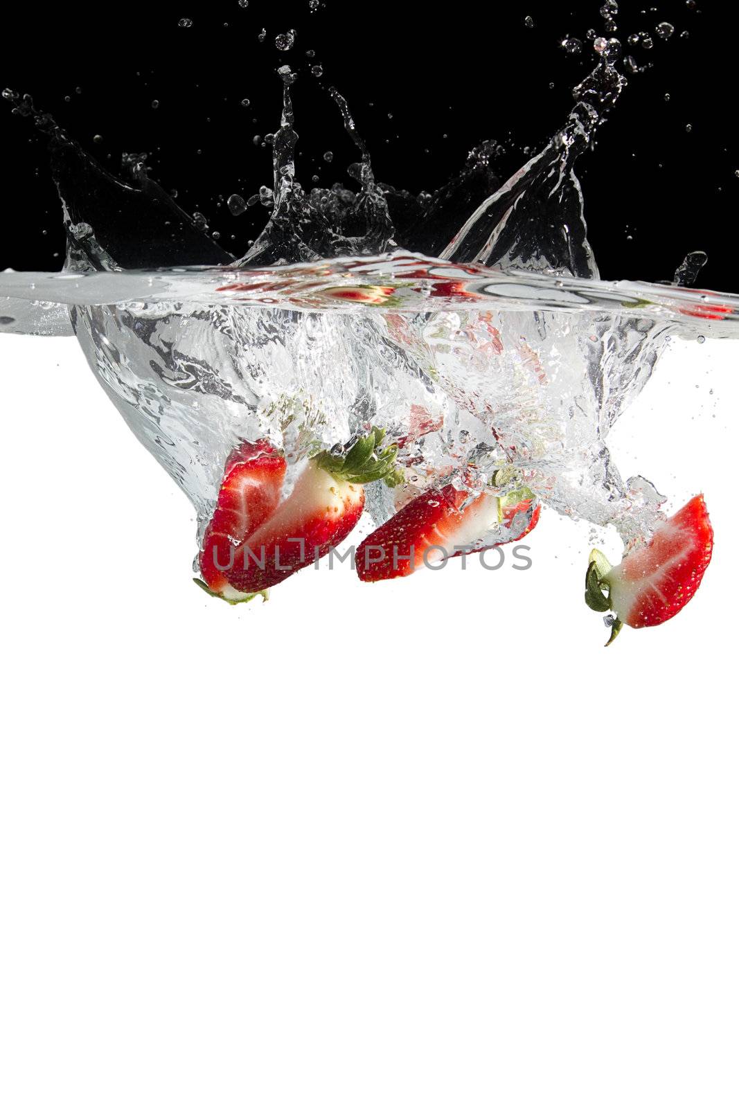 some strawberry pieces thrown in water with black and white background