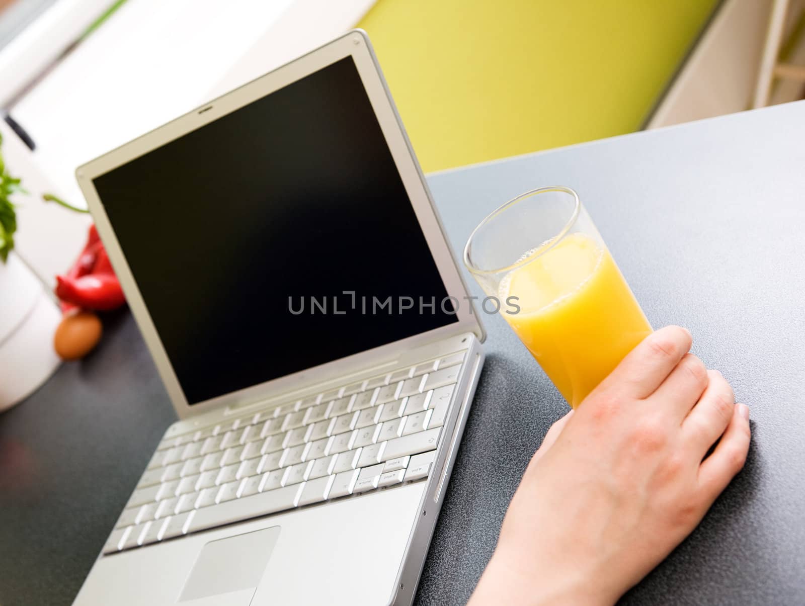 A person using the computer in the kitchen;