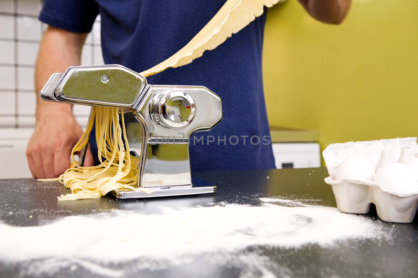 Fettuccine coming out of a manual pasta machine