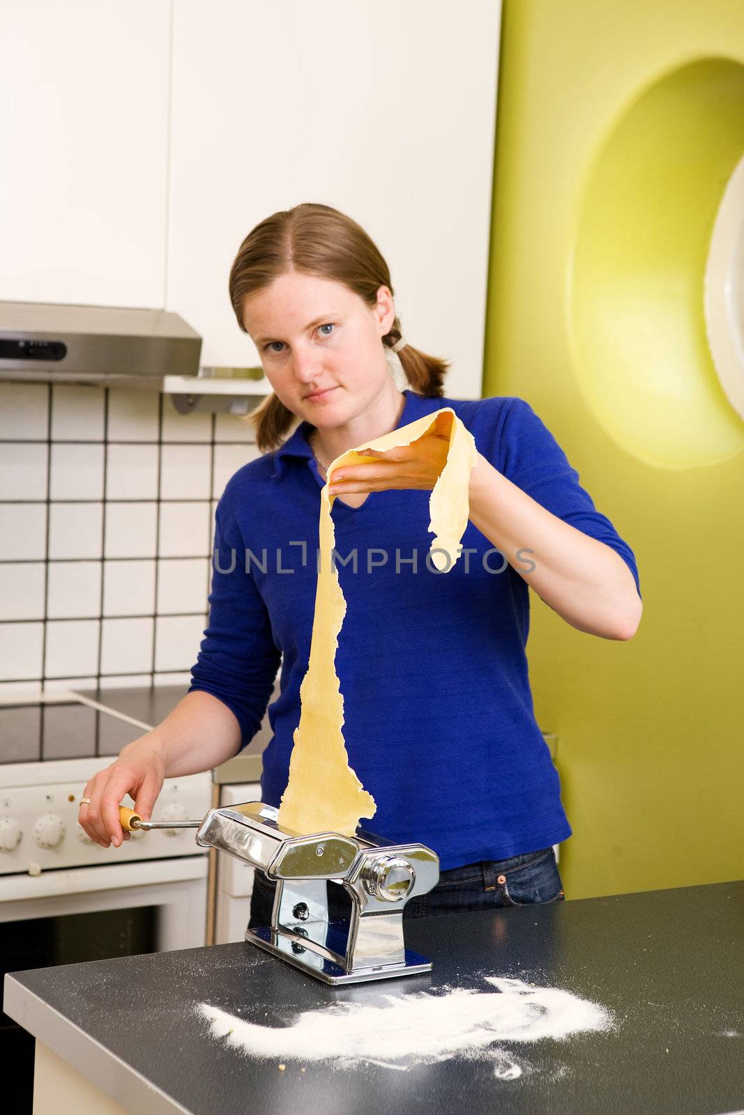 A young woman making pasta in an apartment kitchen.