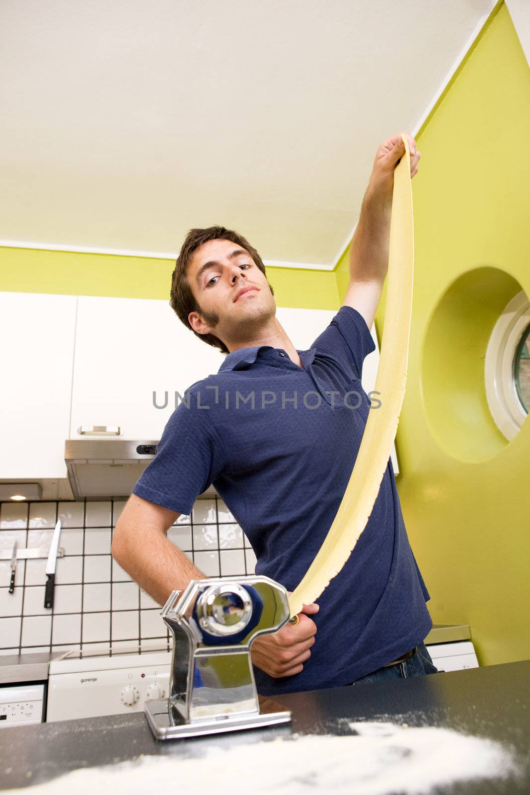 A male proudly showing off his homemade pasta at home in the kitchen