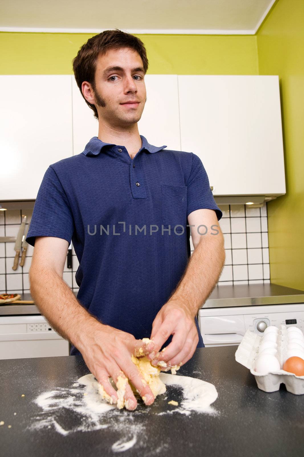 A happy male in the kitchen making pasta by hand and getting messy