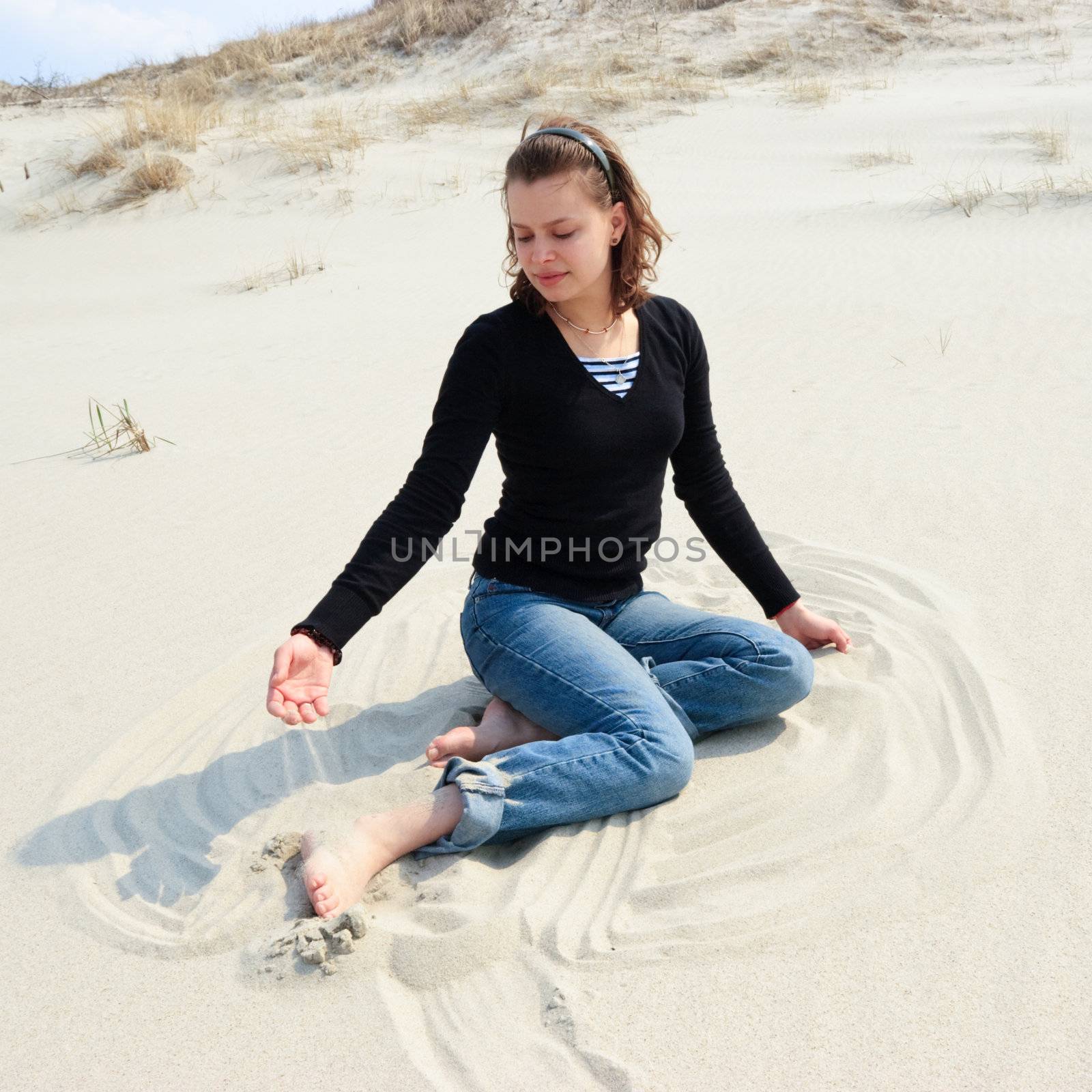Young woman playing with sand on dune at Couronian lagoon