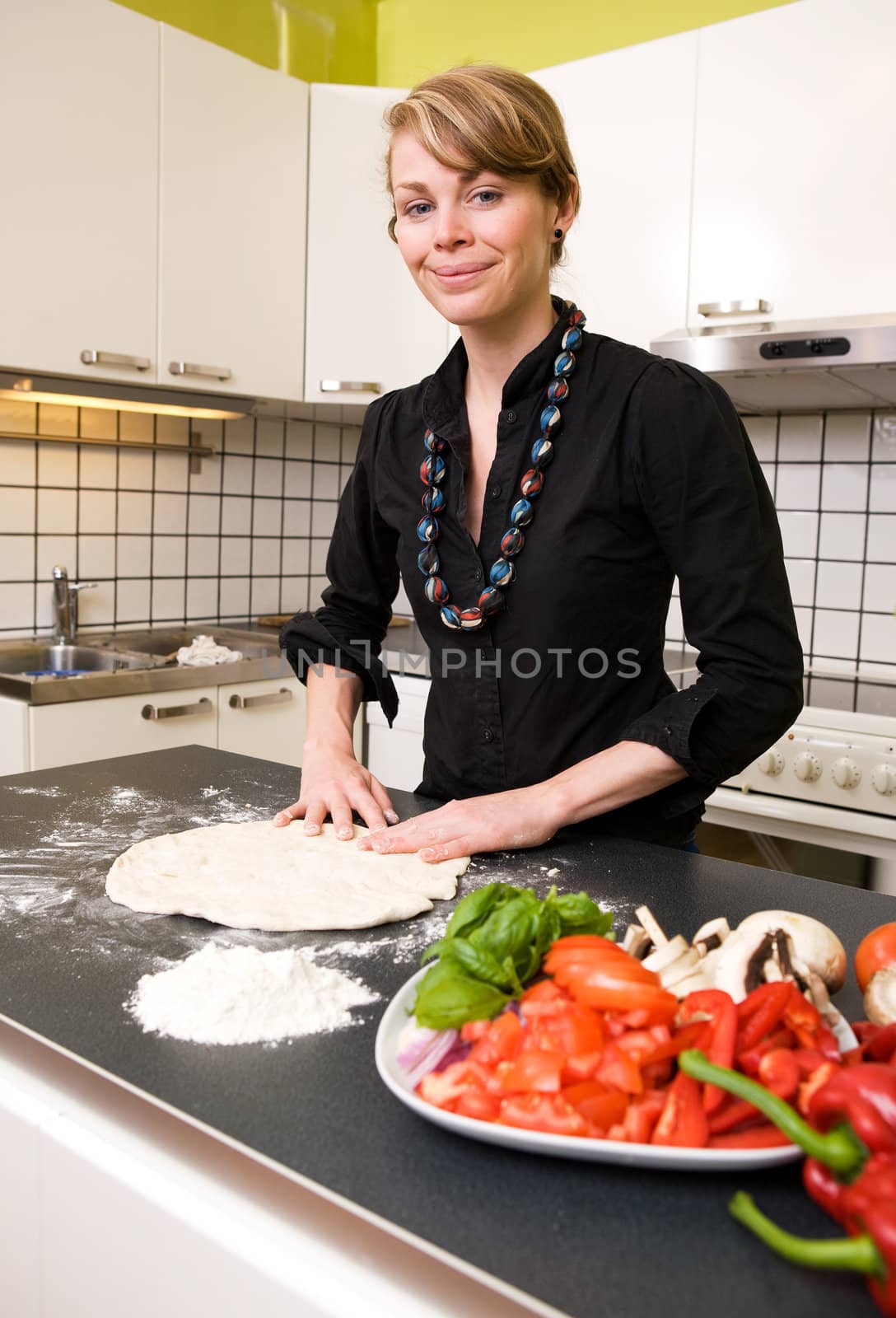 A young woman is making pizza dough on the kitchen counter at home in her apartment. Shallow depth of field with focus on the models face and hands.