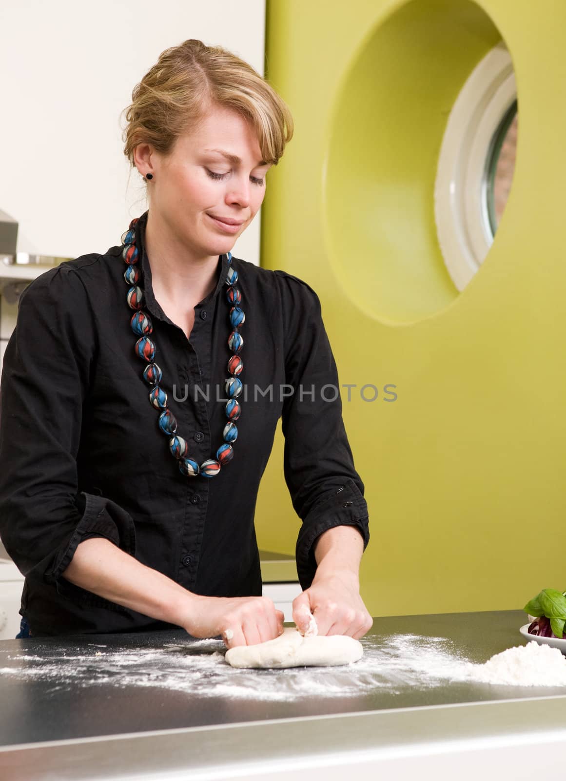 A young woman is making pizza dough on the kitchen counter at home in her apartment.
