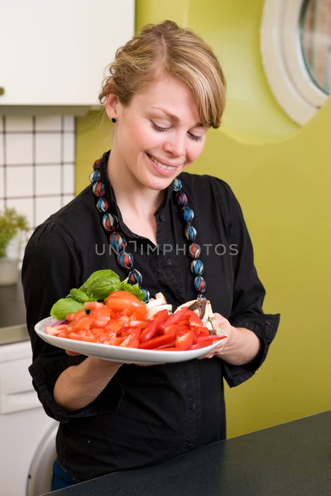 A female in the kitchen looking down on a tasty plate of vegetables - Shallow depth of feild is used to isolate the womans face.