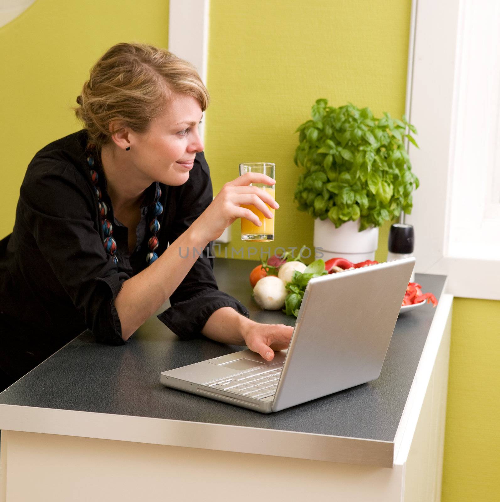 A female eating lunch while using the laptop at home in the kicthen.