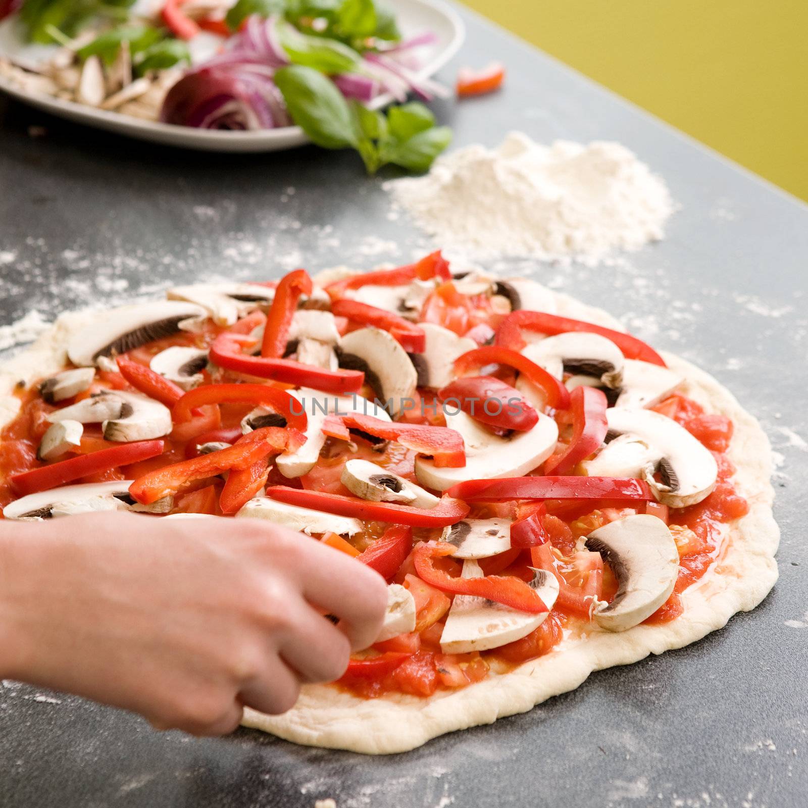 A young female making an italian style pizza at home in her apartment kitchen.