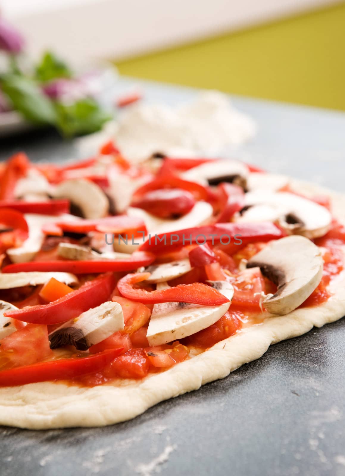 A homemade pizza sitting on the counter ready to be put in the oven. - Shallow depth of field is used to isolate the pizza.
