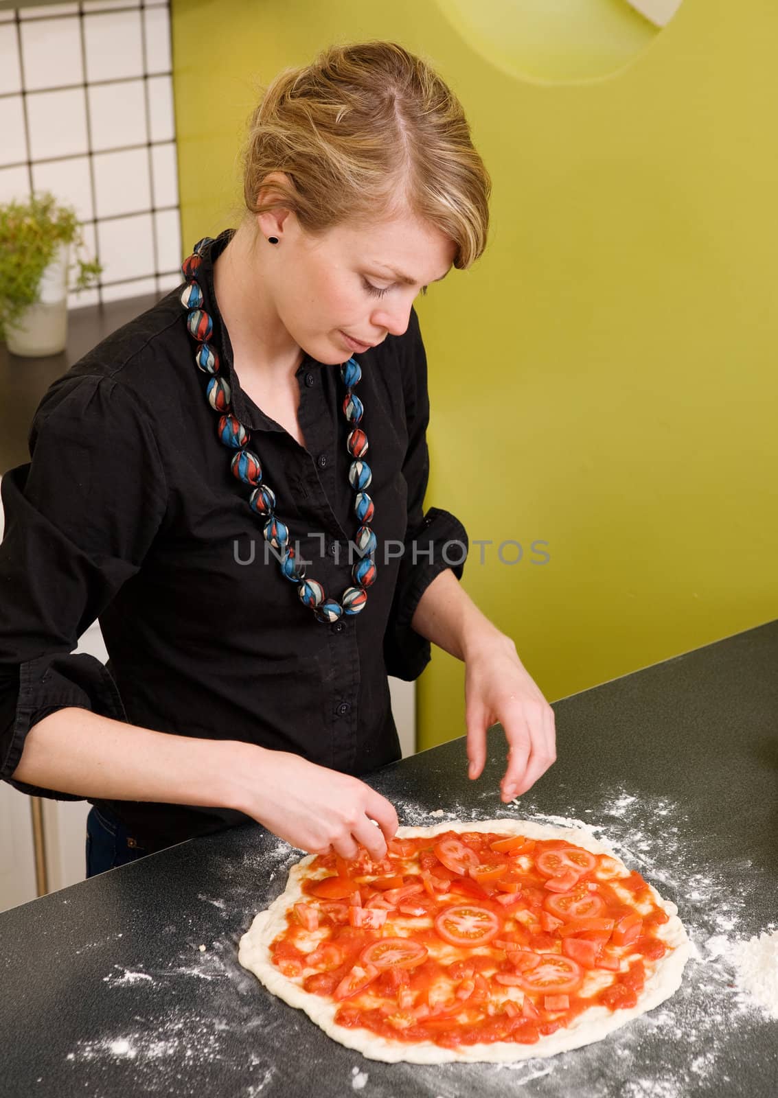 A young female making an italian style pizza at home in her apartment kitchen.