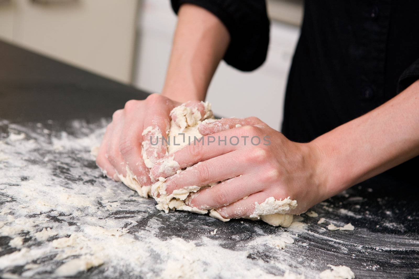 A young woman makes bread on the counter at home in the kitchen.