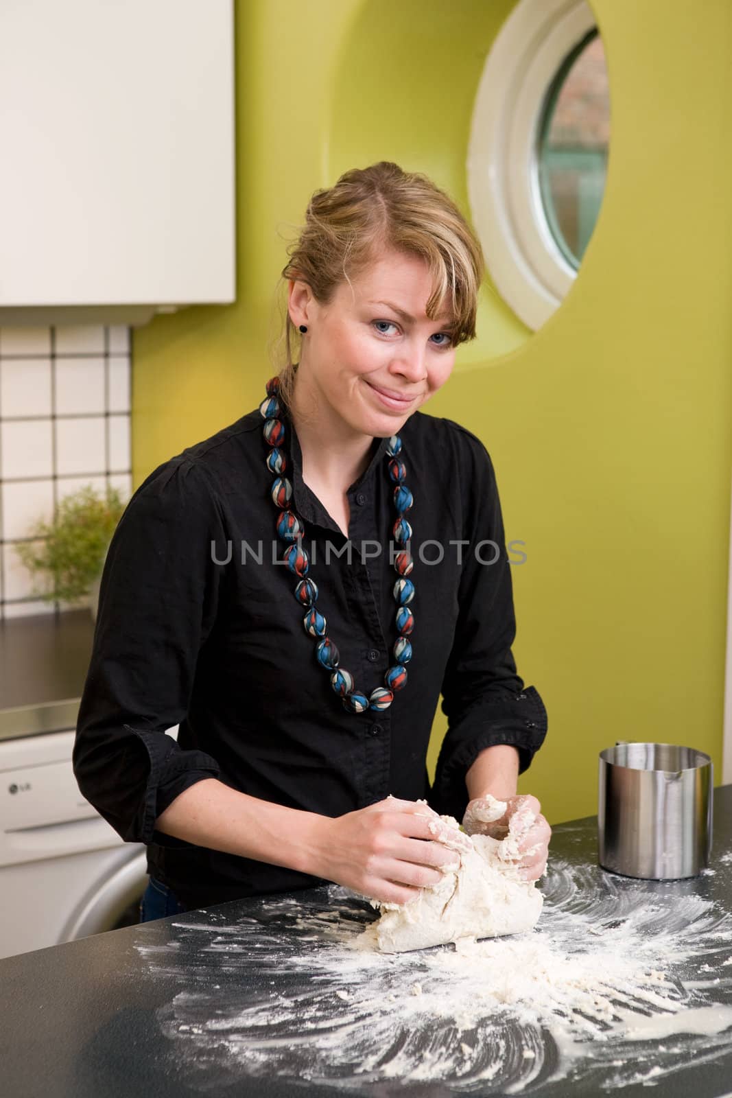 A young woman makes bread on the counter at home in the kitchen.