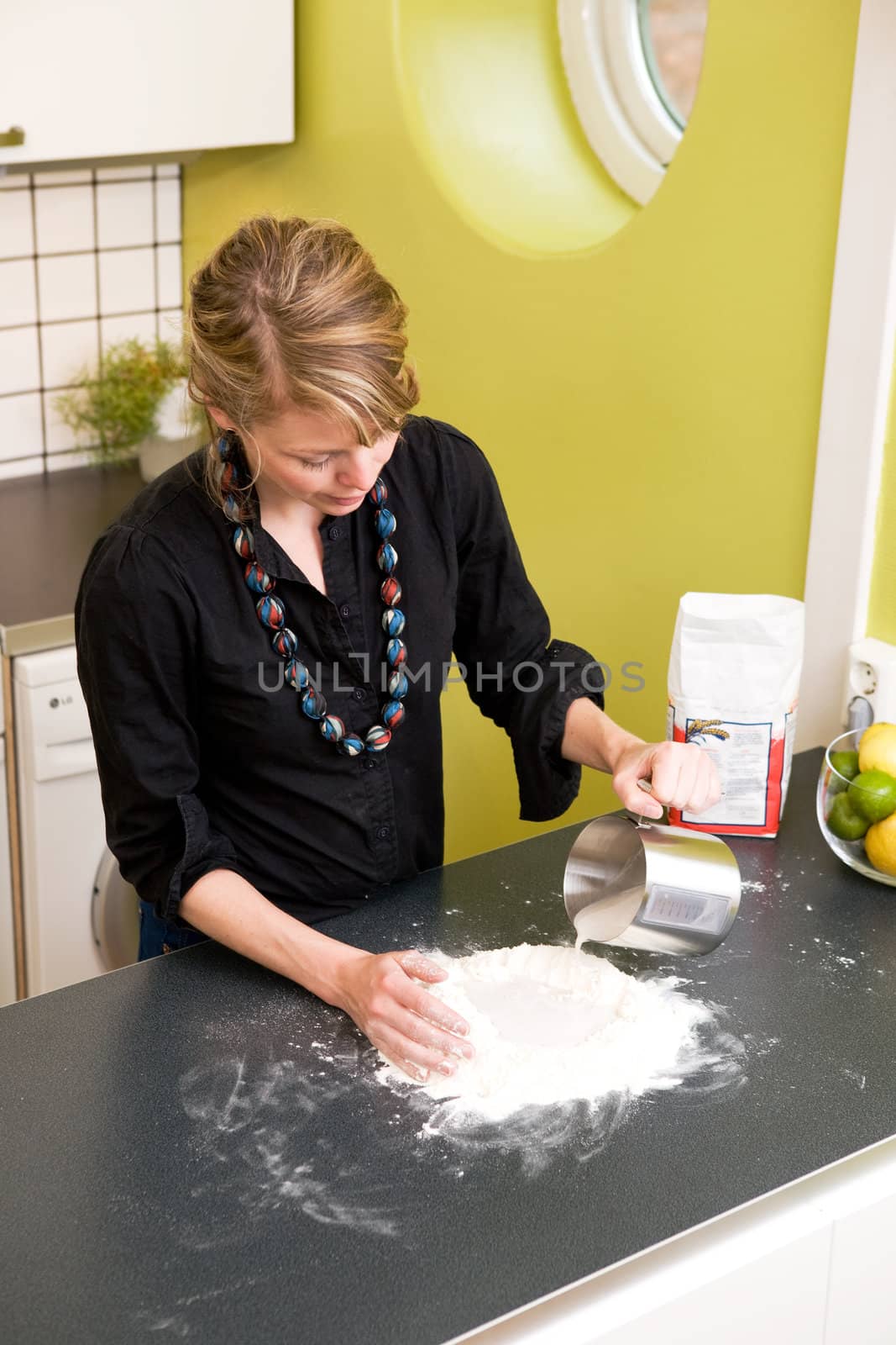 A young woman makes bread on the counter at home in the kitchen.