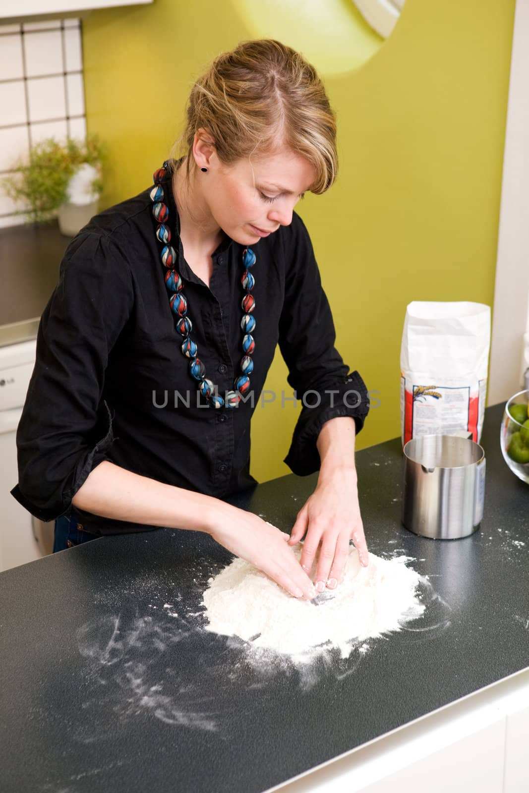 A young woman makes bread on the counter at home in the kitchen.