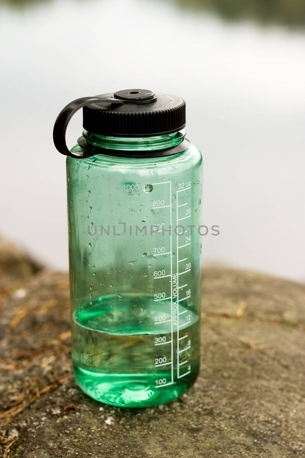 A green water bottle sitting in nature.