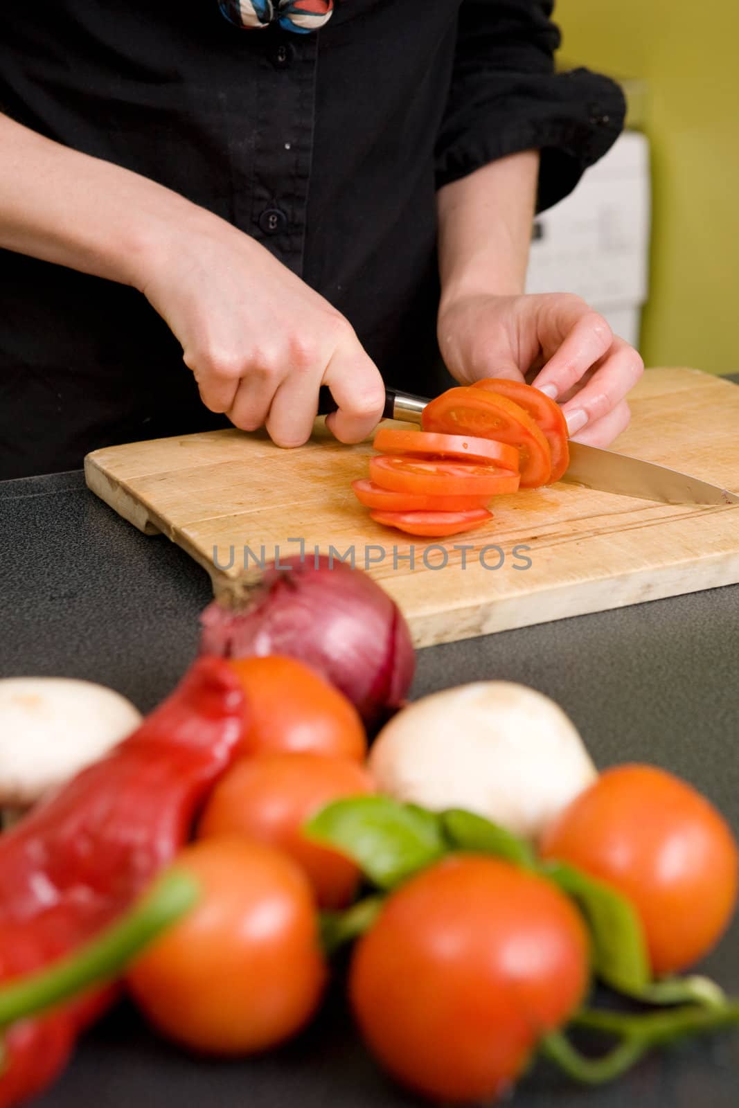 A detail image of a woman slicing tomatoes on a cutting board at home. - shallow depth of field with the focus on the tomato and knife