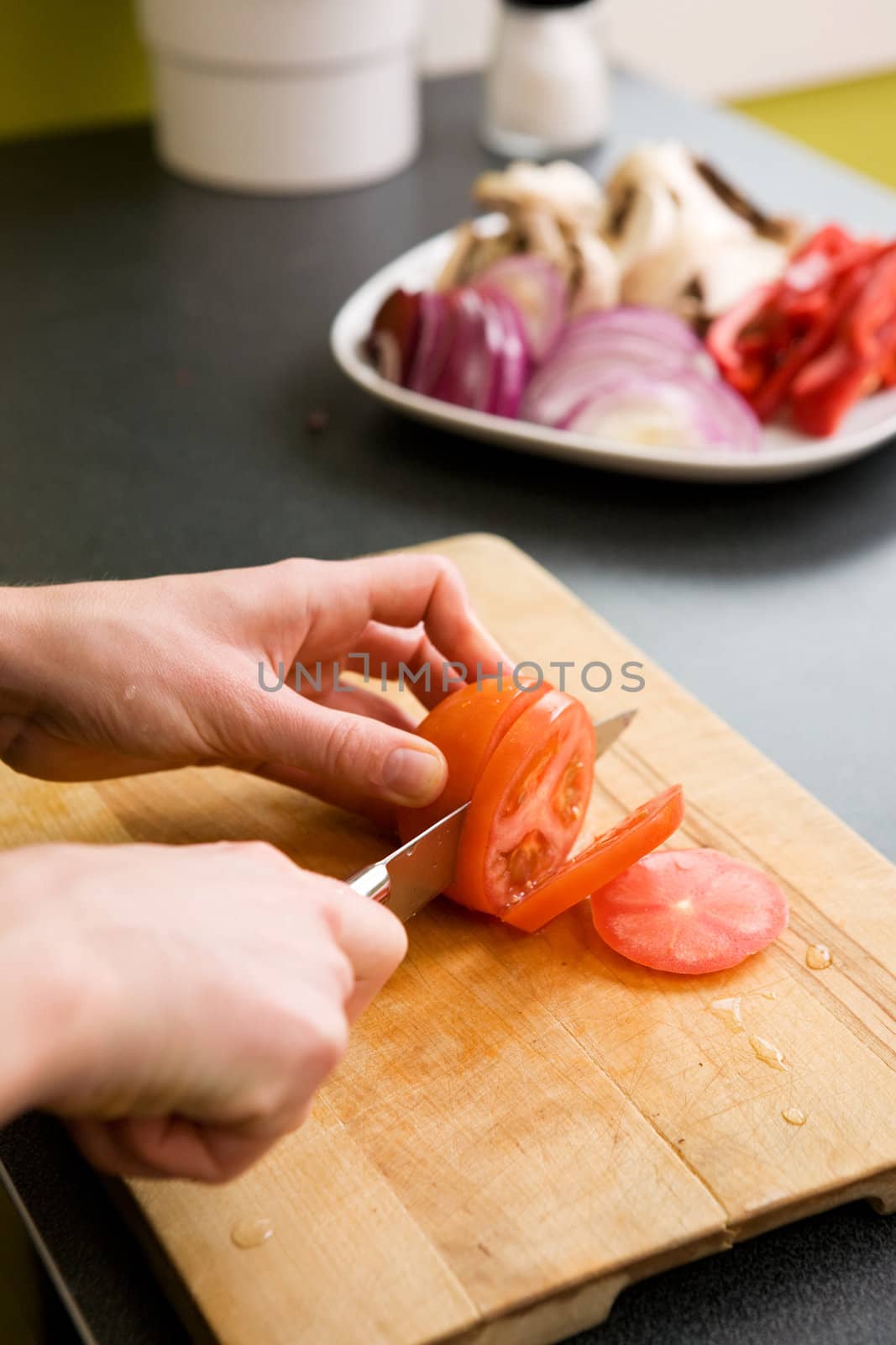 A detail image of a woman slicing tomatoes on a cutting board at home. - shallow depth of field with the focus on the tomato and knife