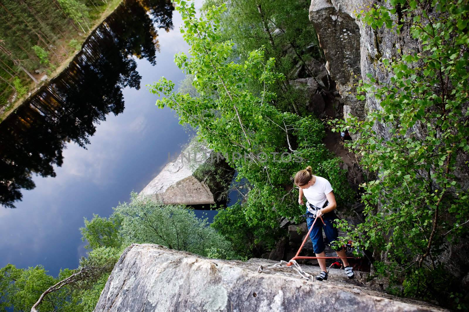 A female climber, repelling down a steep rock face (crag)