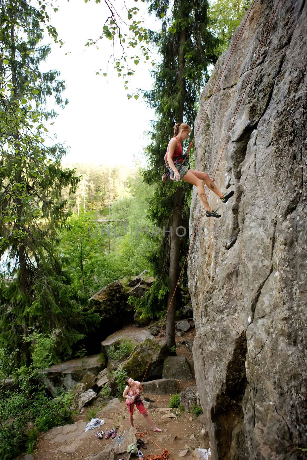 A female climber, repelling down a steep rock face (crag)
