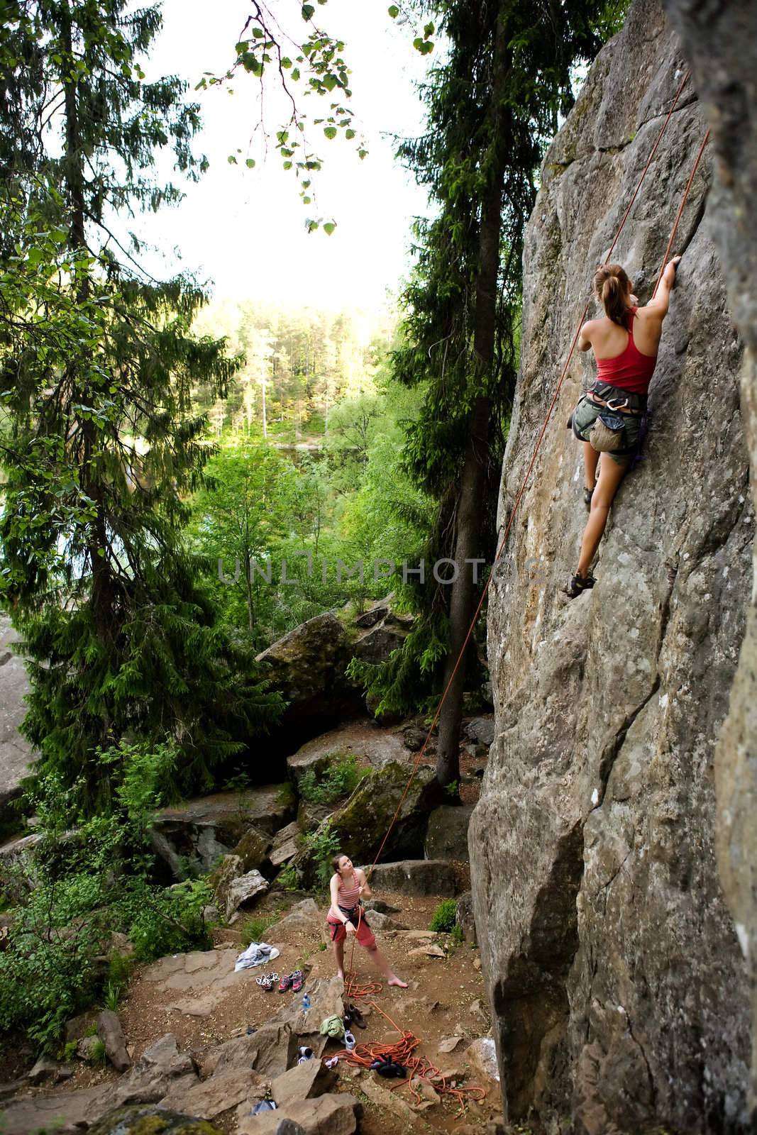 A female climber, climbing using a top rope on a steep rock face (crag)