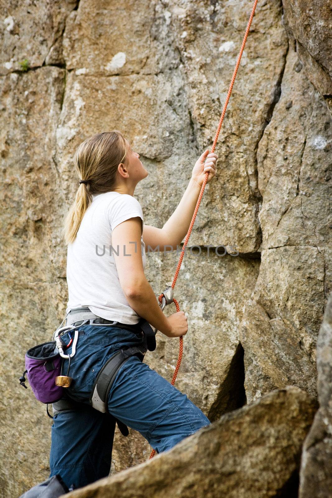 A female belaying a climbing outdoors