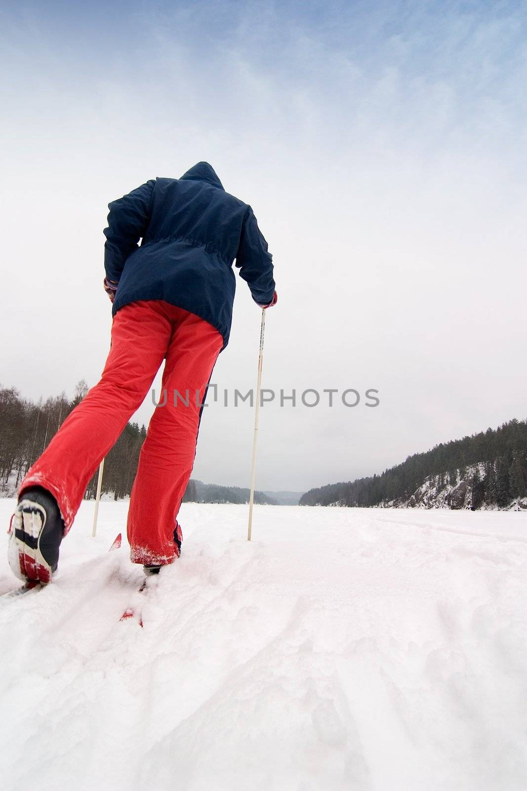 A cross country skier out on a refreshing trip over a frozen lake.