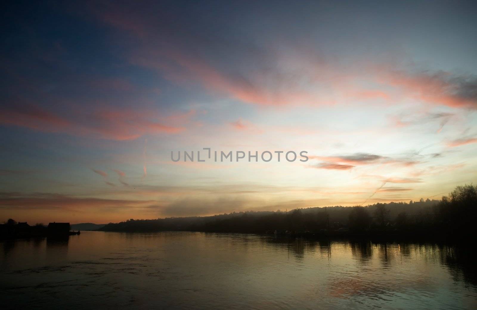 A river near the ocean at sunset with fog and mist.