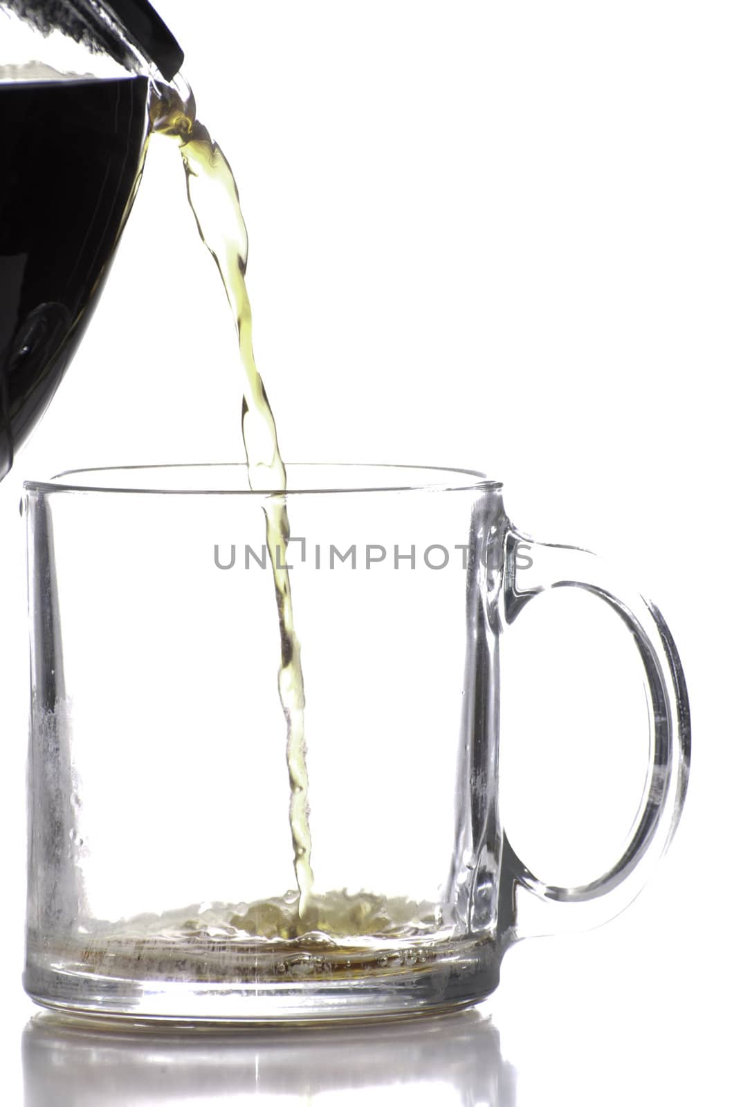 Coffee being poured into a clear coffee cup, shot against a white background