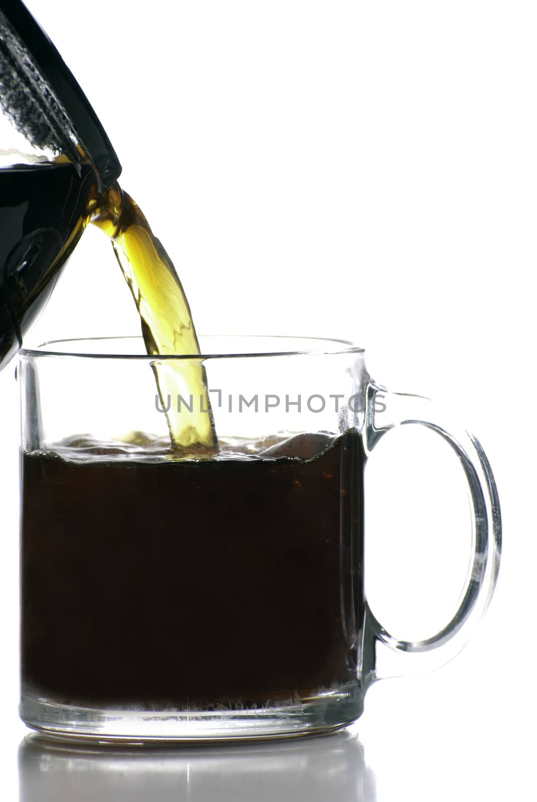 A morning coffee is being poured into a clear glass coffee cup, shot against a white background