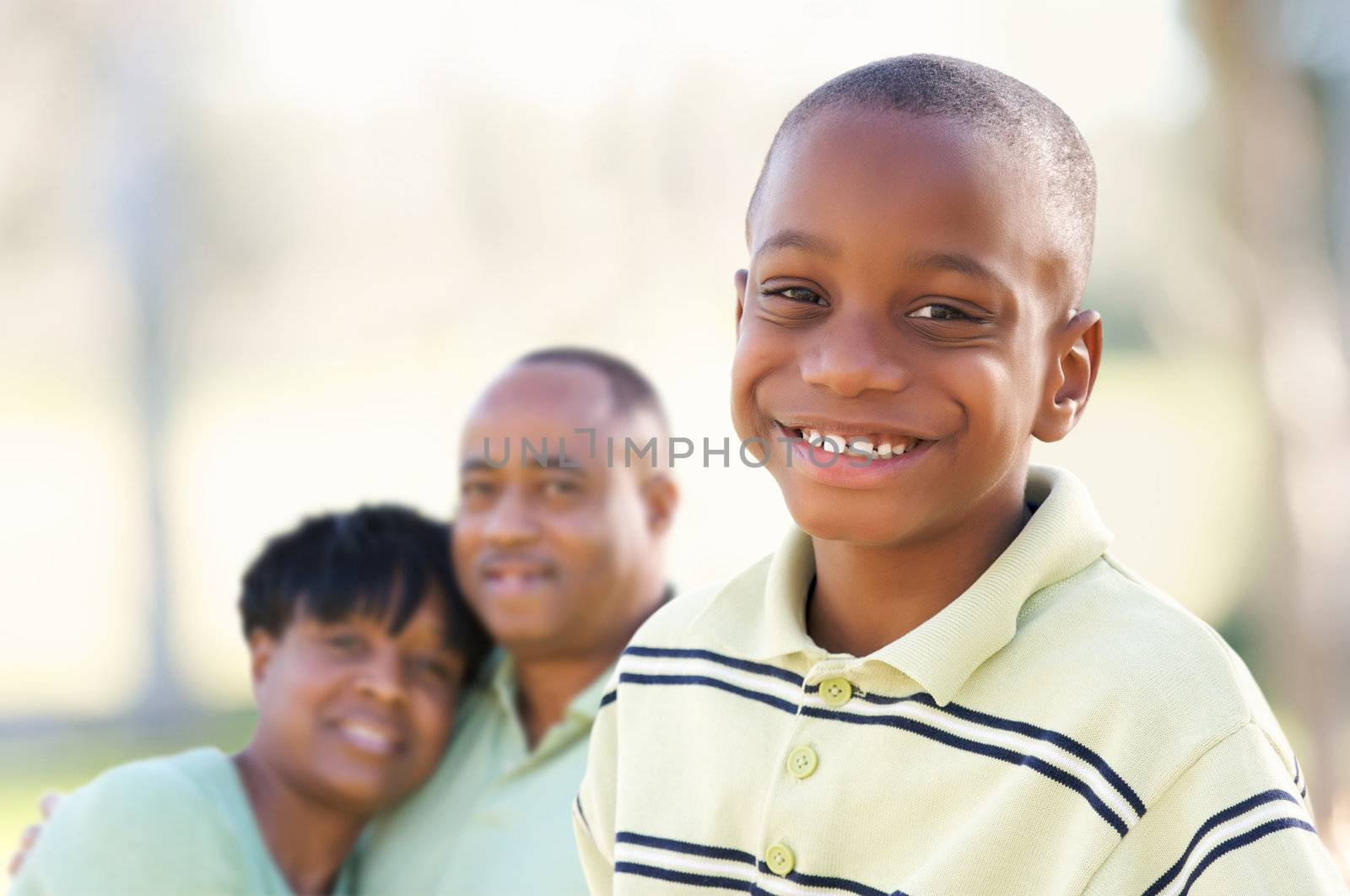 Handsome African American Boy with Proud Parents Standing By in the Park.