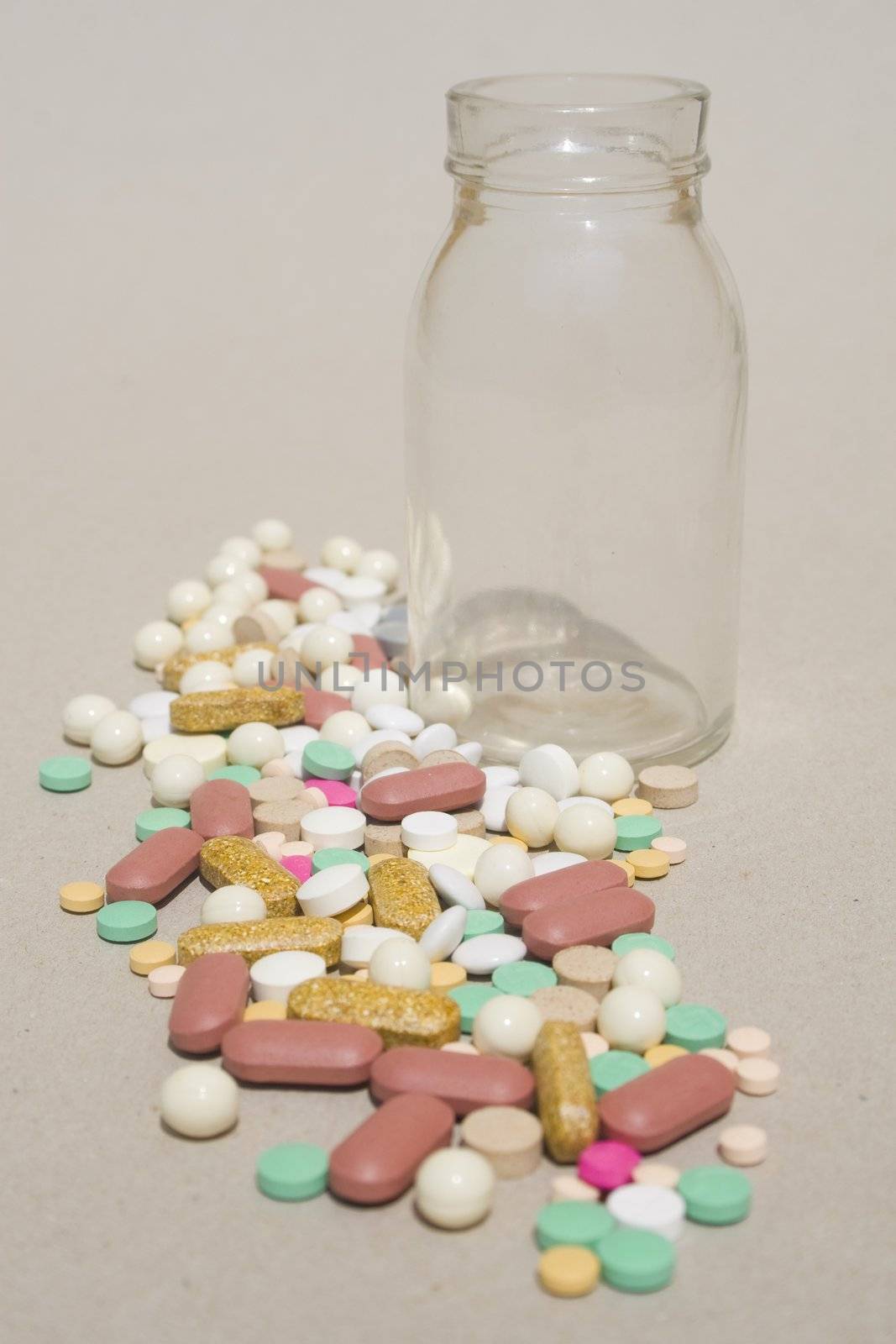 Empty glass bottle and pile of spilled pills
