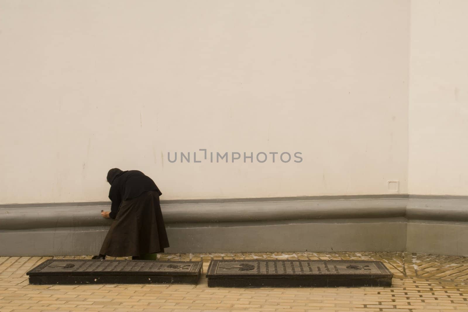 Nun cleaning the wall of a large cathedral