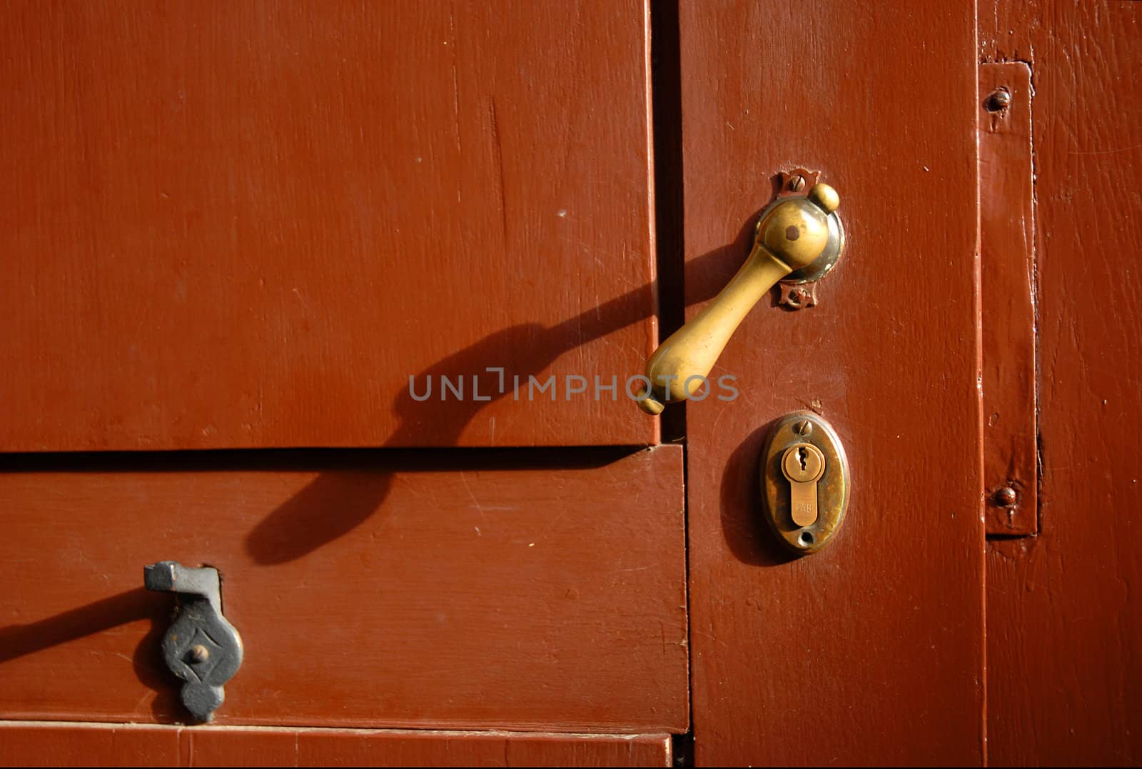 Bronce latch of a red wooden door 