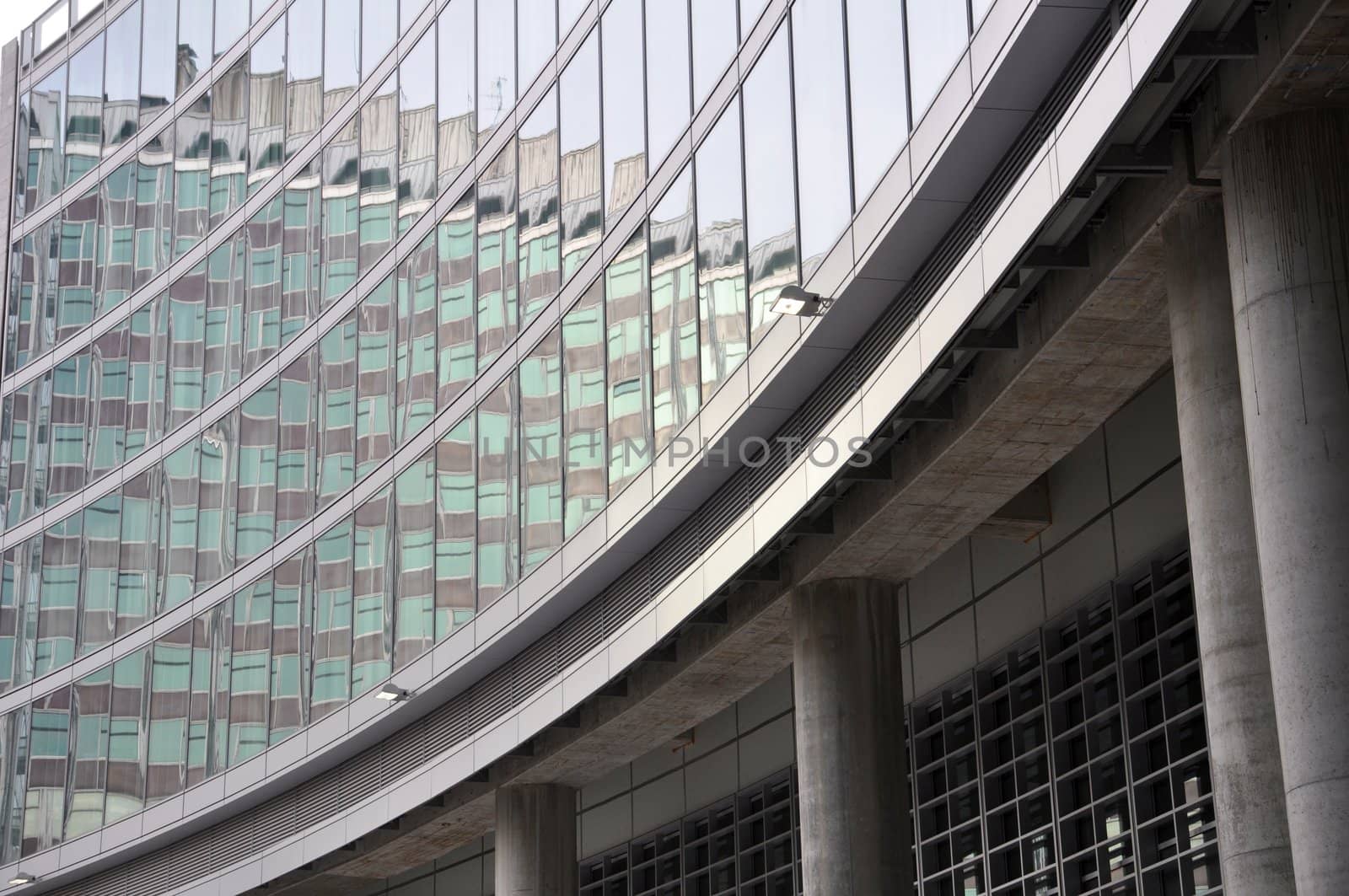 A modern office building facade made of steel and glass is reflecting another building