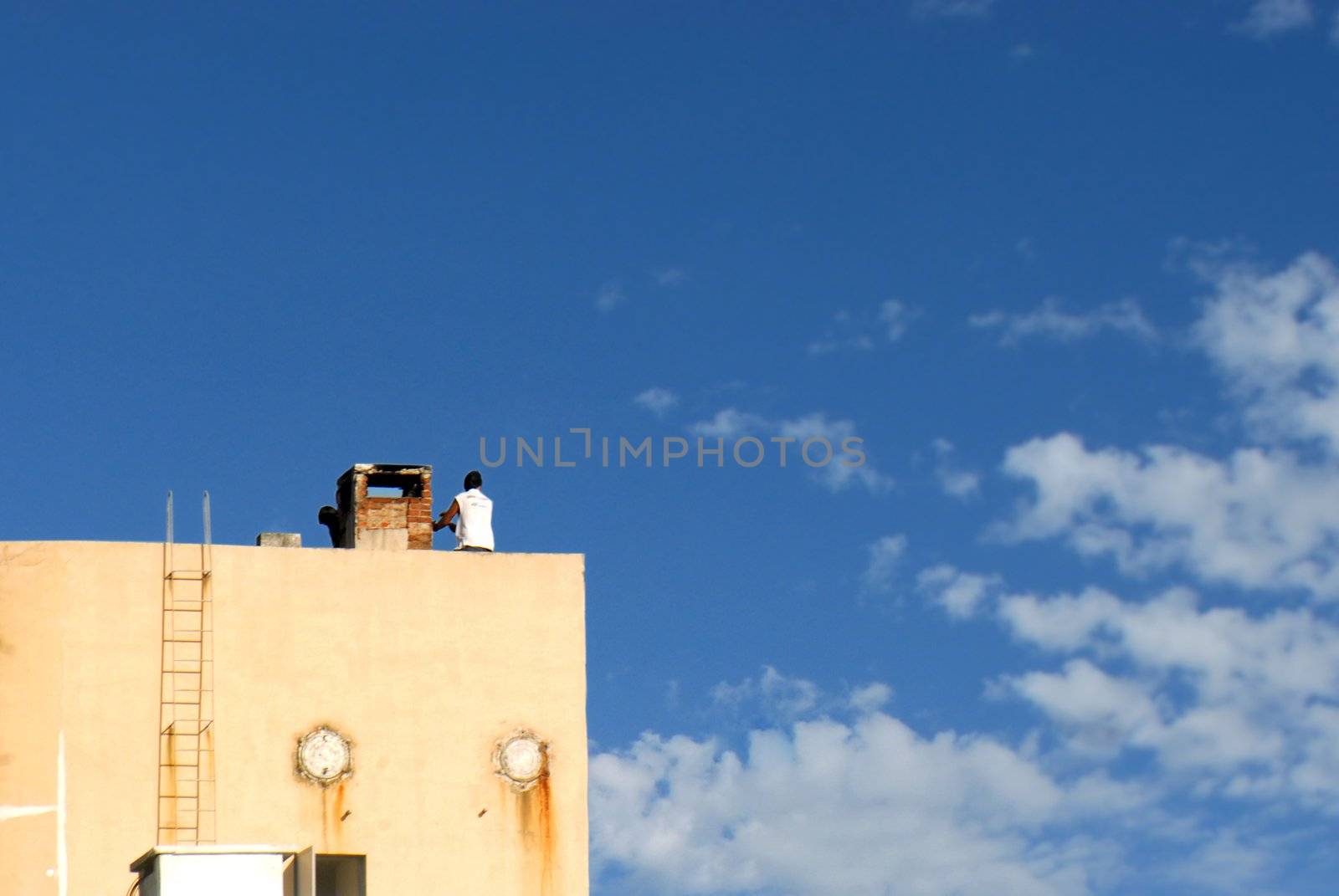 Man on a water tank over a blue sky background