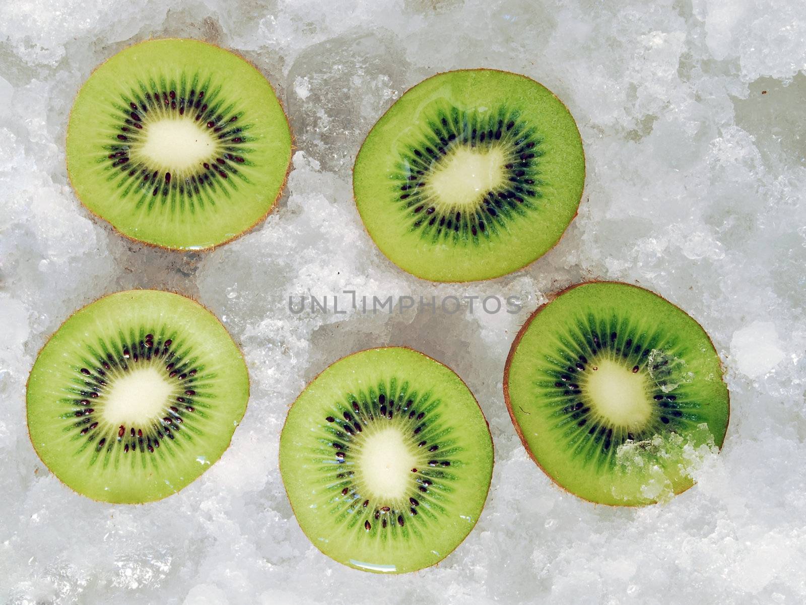 Upper view of five halves fresh fruit on ice cubes. Cut kiwis on ice background
