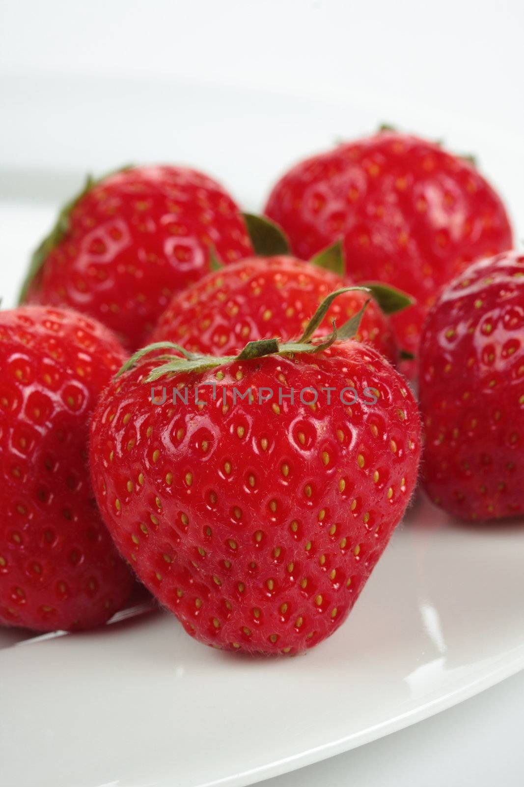 a bunch of strawberries on a plate over white background