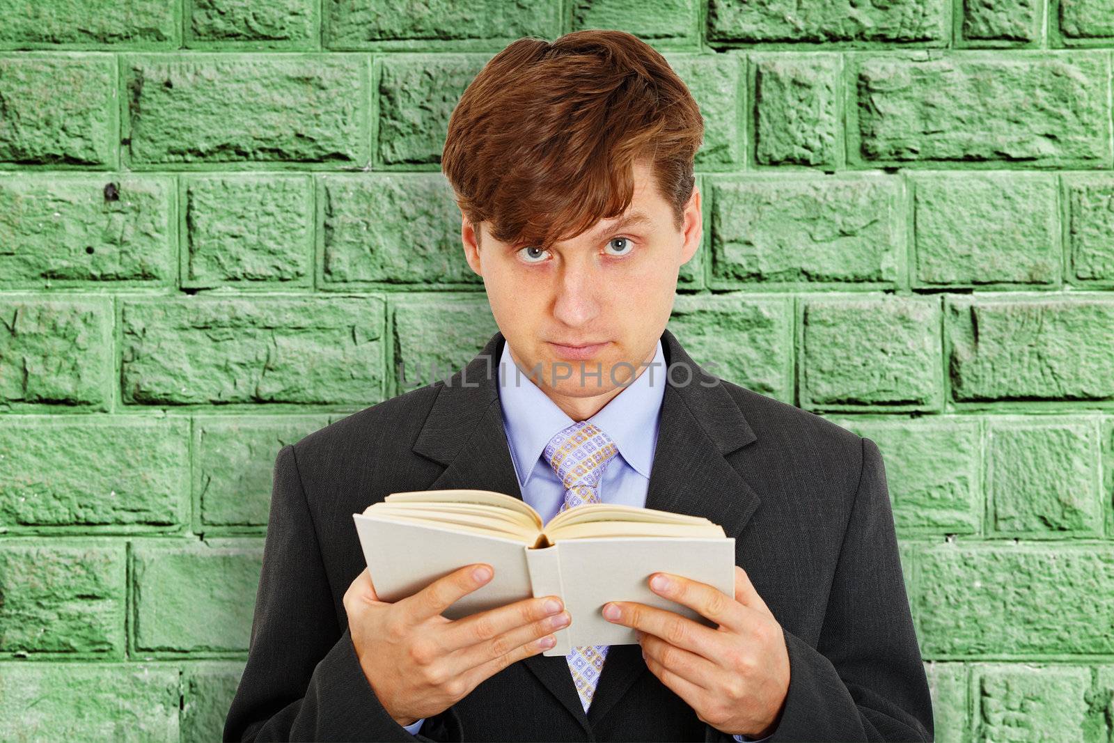 Person reads a book on the background of the stone wall