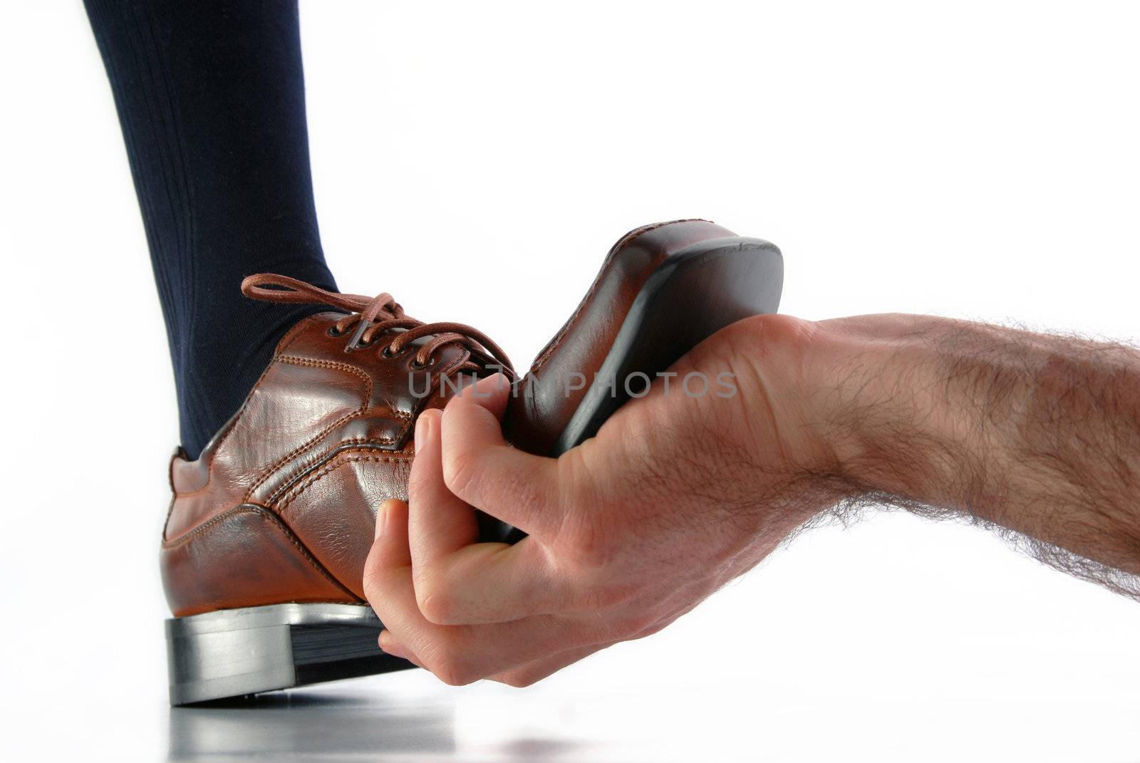 Hand holding back a male shoe on white background