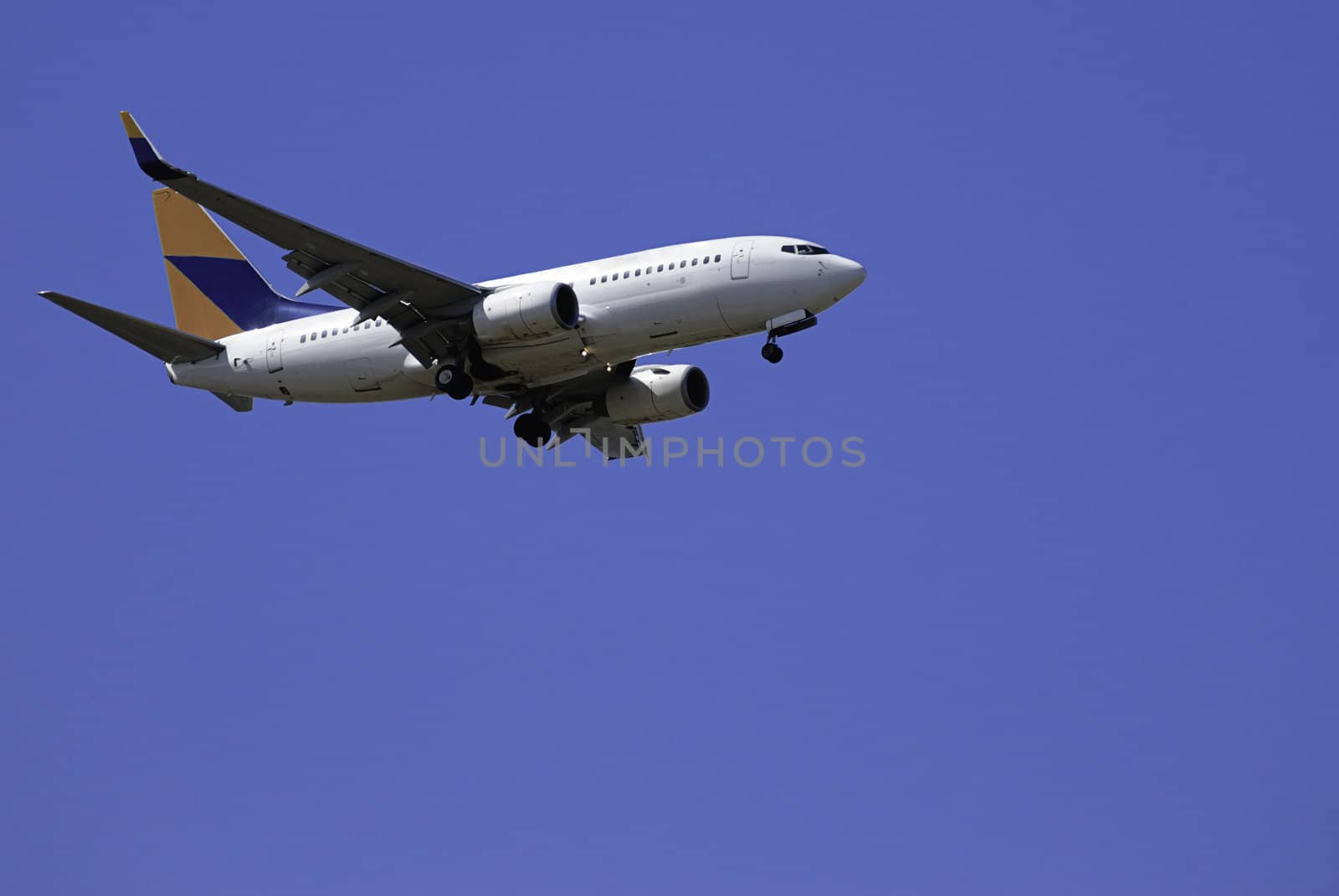 A large jet landing with its gear down, shot against a blue sky - color scheme and design changed