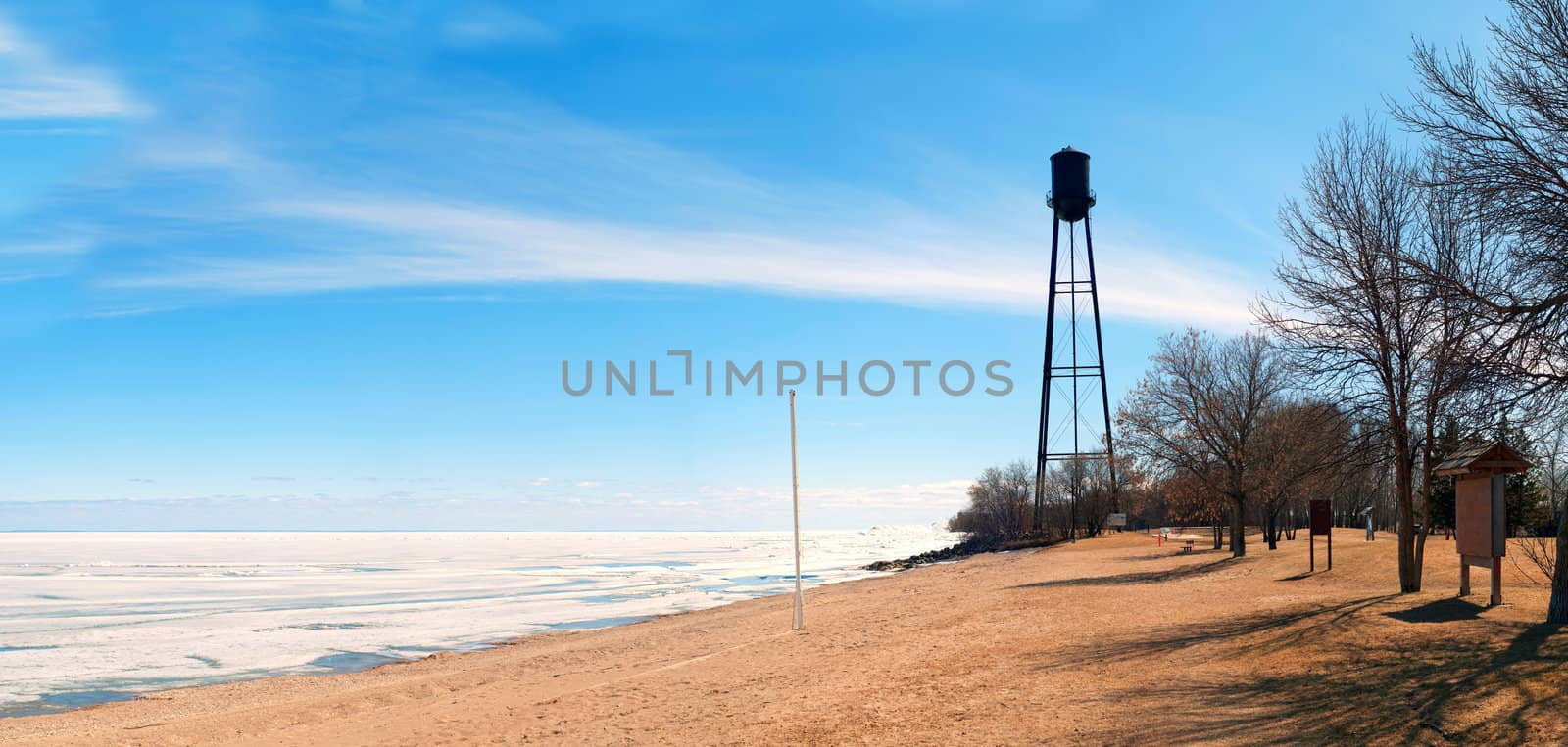 A rural beach in the spring with the lake still frozen, shot with a blue sky