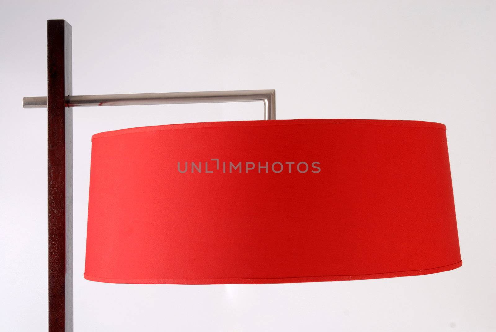 Metallic and wooden contemporary floor lamp detail. Red lampshade. Isolated on white background