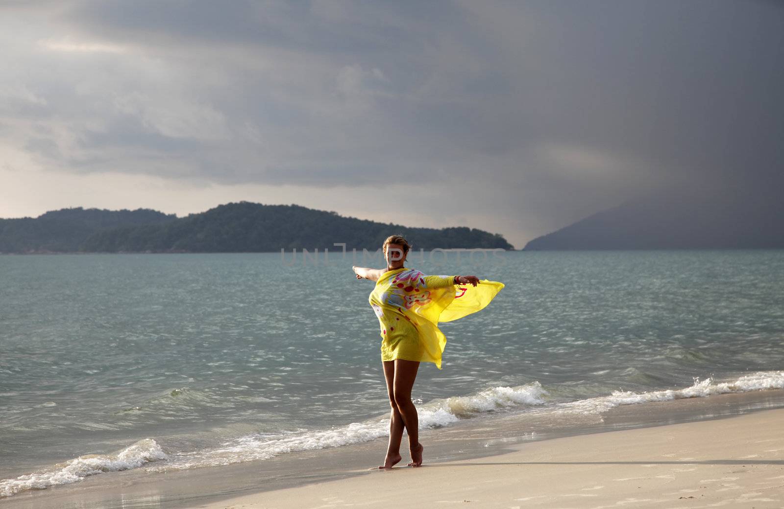 Woman in a yellow scarf coast of the sea before storm