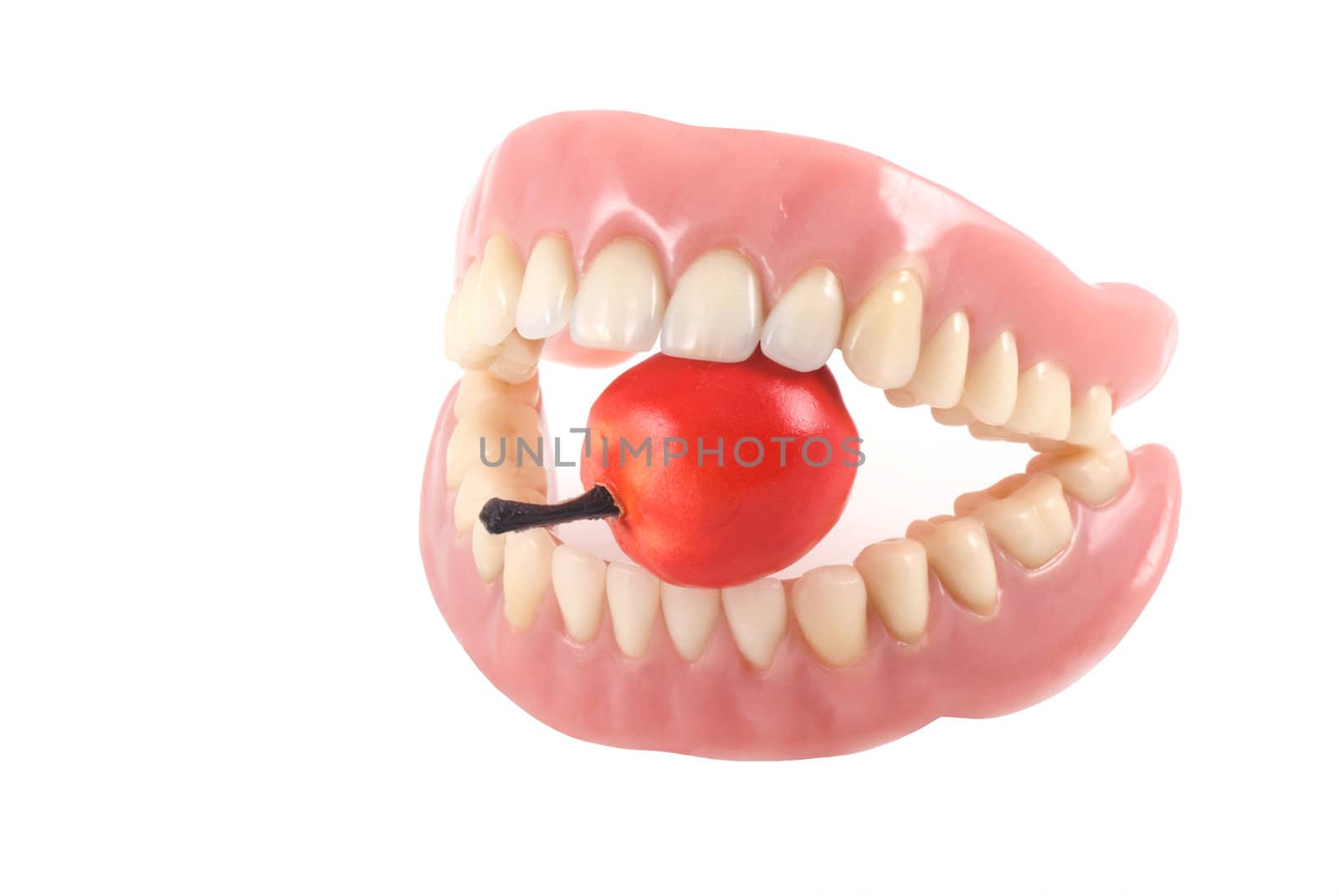 Dentures with little fake apple, isolated on a white background.