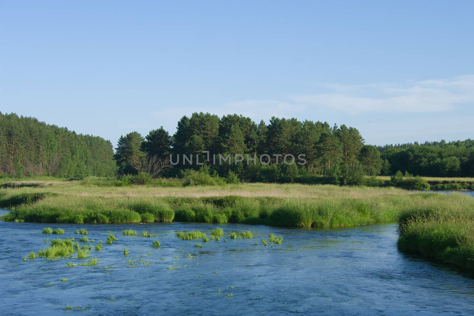 Tranquil river flowing through the meadows before the sunset