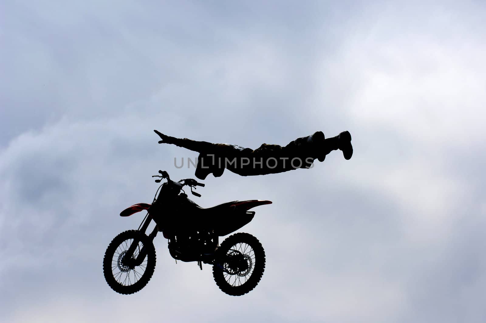 A freestyle motocross rider performs a trick (superman) during a competition.