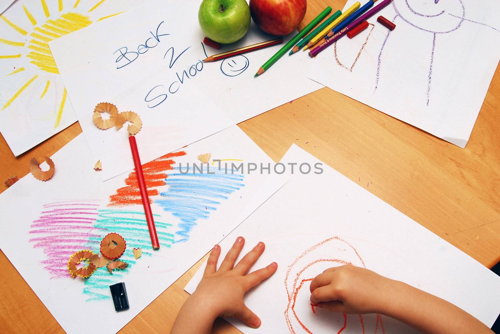 Little hands drawing between school supplies and apples