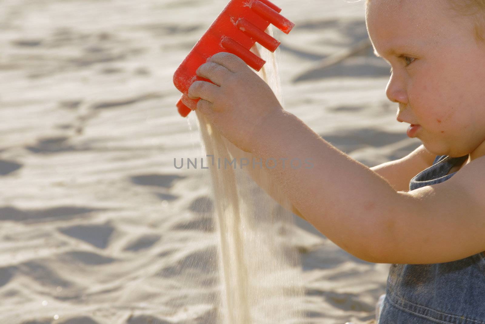 Baby girl playing with sand by cienpies