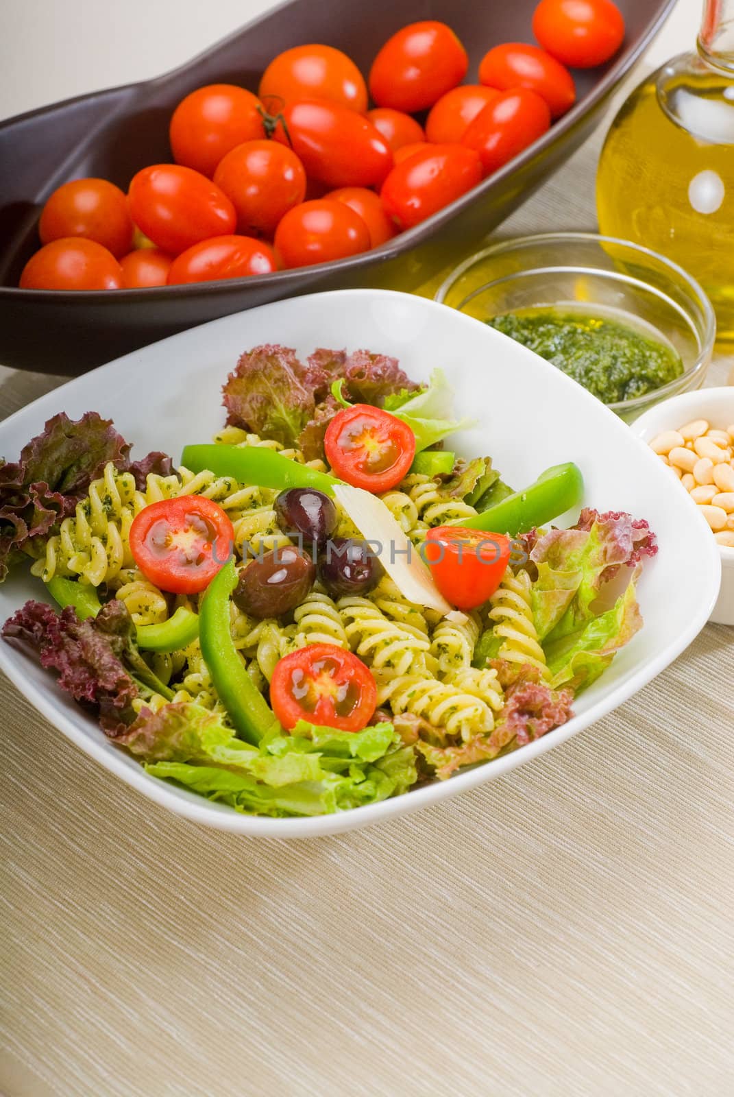 fresh healthy homemade italian fusilli pasta salad with parmesan cheese,pachino cherry tomatoes, black olives and mix vegetables ,dressed with extra-virgin olive oil and pesto sauce